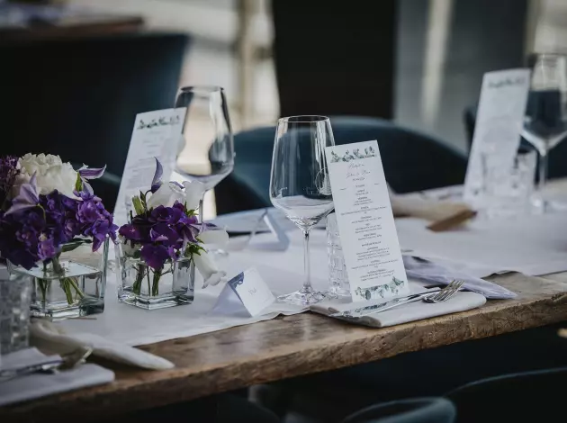 Hochzeit im am kai Hamburg – gedeckte Tafel mit lila Blumenarrangement und eleganten Menükarten