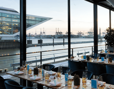 Business Event im Séparée mit Wintergarten – festlich gedeckte Tische vor großen Fenstern mit Elbblick im am kai Hamburg
